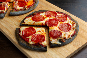 Creative pizza on black dough, three pieces on the board.