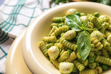 Plate with tasty pesto pasta on table, closeup
