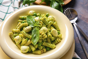Plate with tasty pesto pasta on table