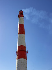 Smoke from a factory chimney against a blue sky. Vertical view.