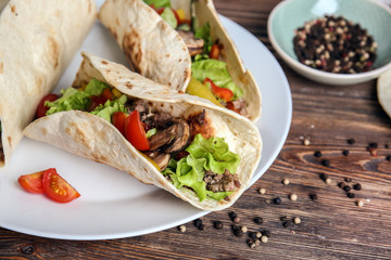 Plate with tasty tacos on wooden table