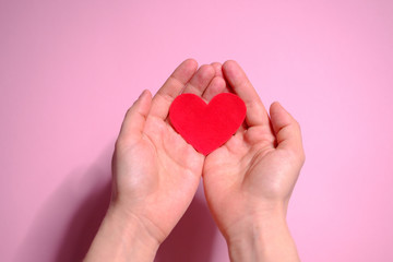 Obraz premium Heart in hands on a pink background. Valentine's Day