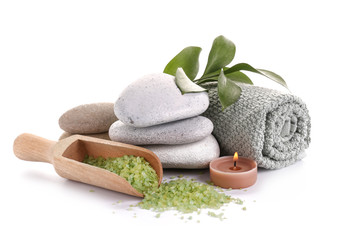 Beautiful spa composition with stones, towel, sea salt and candle on white background