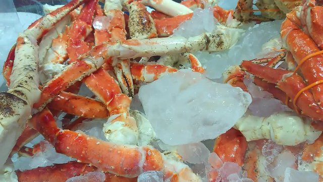 Red king crab legs cooked and cooled on the ice. Delicious seafood and luxury food. Canadian fish market. Smartphone footage.