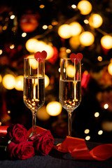 Glasses of champagne on the background of lights with roses and red ribbon