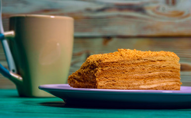 A piece of cake and a cup of coffee on a green wooden background.