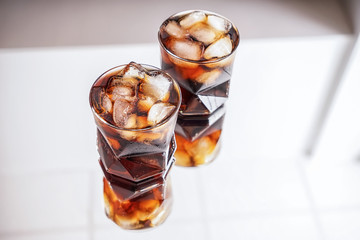 Glasses of tasty cold cola drink on light table
