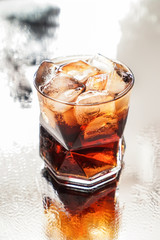 Glass of tasty cold cola drink on light table