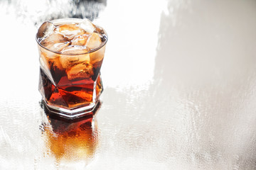 Glass of tasty cold cola drink on light table