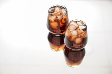 Glasses of tasty cold cola drink on light table