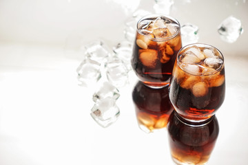 Glasses of tasty cold cola drink on light table