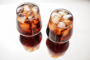 Glasses of tasty cold cola drink on light table