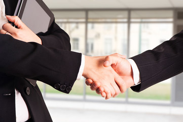 TWO businessman handshake with modern skyscrapers as background