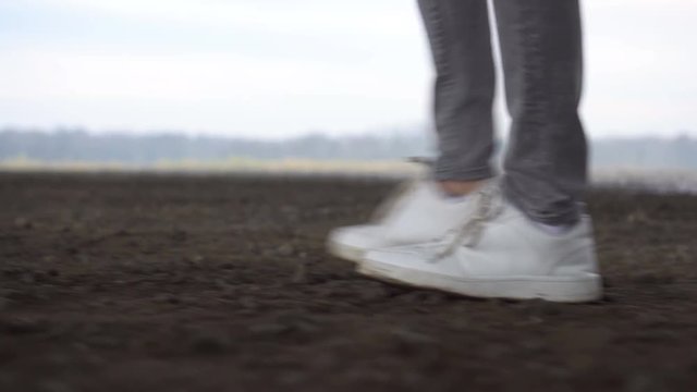 Shot of men feets in sneakers walking on ground road. Nature Environment