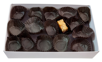 Last piece of candy among empty wrappers in box.