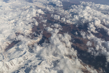 Aerial view from the airplane. Mountains and clouds view from the space