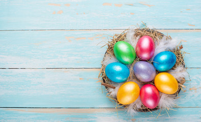 Easter colored eggs in a nest on a wooden background with space