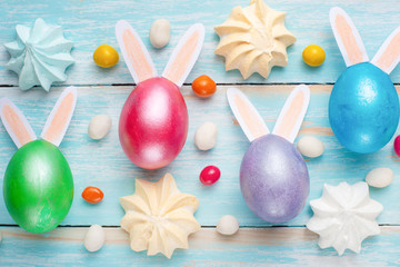 Easter colored eggs with sweets and rabbit ears. Flat lay