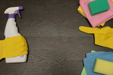 cleaning liquid with rubber gloves rags and sponges on wooden background, copy space.