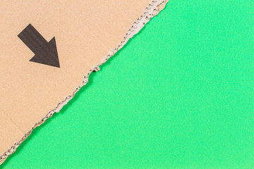 Brown corrugated cardboard ragged edge with black arrow on green background