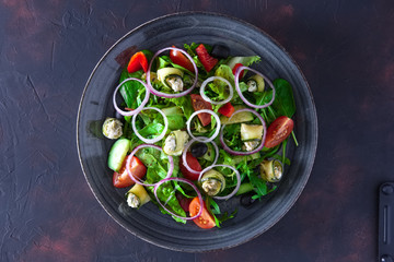 Fresh salad with zucchini stuffed with feta cheese with tomato, red onion rings, cucumber and black olives