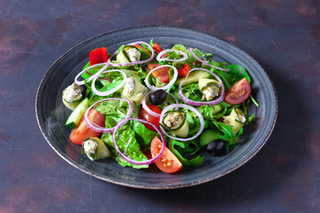 Fresh salad with zucchini stuffed with feta cheese with tomato, red onion rings, cucumber and black olives