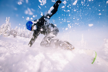 Snowboarder on snowboard rides through snow, explosion. Freeride in winter Ski Resort.