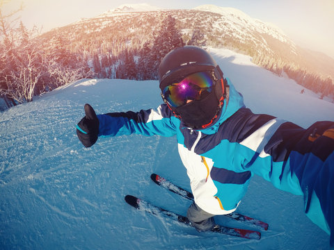 Winter Extreme Sport With Selfie Action Camera. Man Rides On Slopes Skis In Protective Helmet