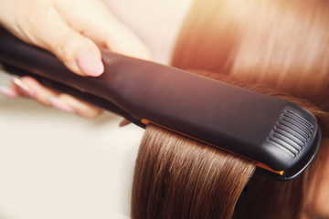 Pulling strands of hair with professional ultrasonic iron tool. Spa care.