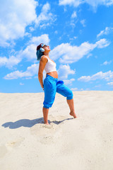 Old sporty woman standing in the desert against the sky blue with clouds.