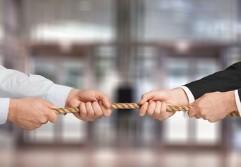 Tug war, two businessmen pulling a rope in opposite directions