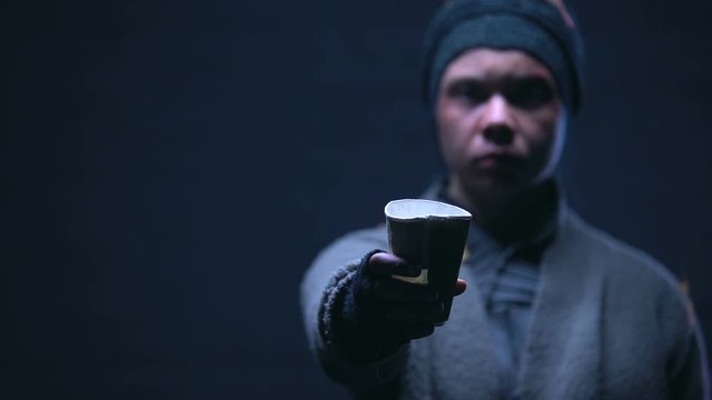 Beggar showing paper cup into camera, asking for money and donations, charity