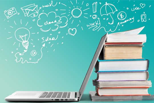 Stack of books with laptop on table