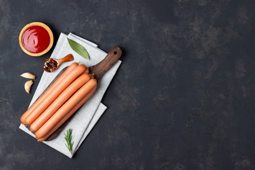 Raw frankfurter sausages with ketchup on cutting board. Top view. Copy space for text.