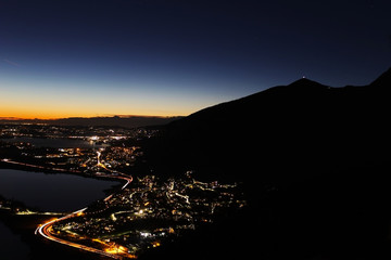 Night panorama from the Alps over northern Lombardy with city lights pollution and mountains silhouette