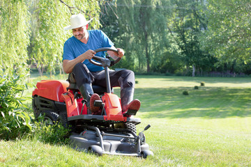 young man, father with son with a grass trimmer mows the lawn. Meadow in summer. Spring in the green garden