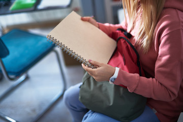 Young woman in pink sweatshirt holding spiral notebook