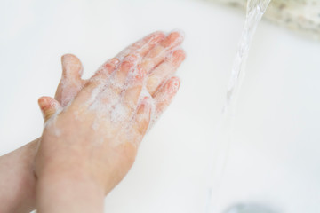 Fototapeta premium Young child washes hands with a sparkly green bar of soap; child demonstrates cleaning hands with soap and water