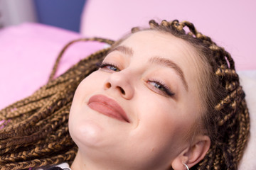 Eyelash Extension Procedure. Woman is smiling at camera in beauty salon. Close up face with Long...
