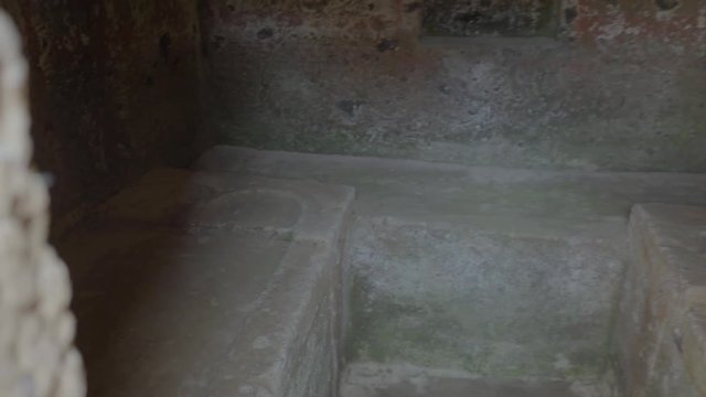 View inside Etruscan burial tomb chamber puling back through large stone doorway.