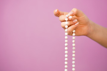 Woman, lit hand close up, counts Malas, strands of gemstones beads used for keeping count during...