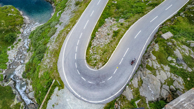 Drohnenaufnahme eines Motorradfahrer in Schr&auml;glage auf einer asphaltierten Stra&szlig;e