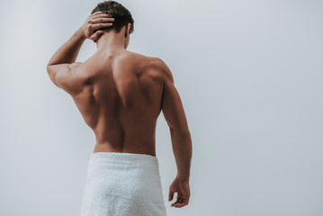 Muscular man in white towel touching his hair