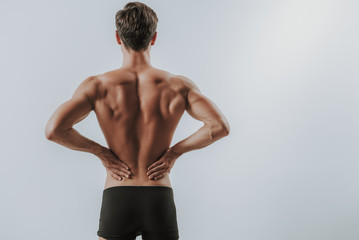 Waist up of muscular man putting hands on the back