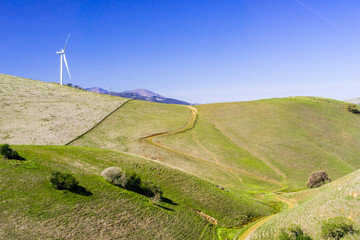 Wind turbines on the top of green hills in east San Francisco bay area on a clear, sunny day,...
