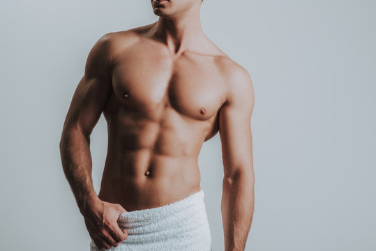 Muscular man having white towel on his hips and standing alone