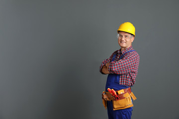Electrician with tools wearing uniform on gray background. Space for text - Powered by Adobe