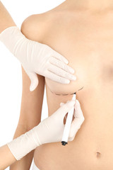 Doctor drawing marks on patient's breast for cosmetic surgery operation against white background, closeup
