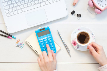 Female hands working on calculator. Office desktop on white background.