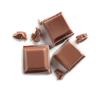 Pieces of tasty milk chocolate on white background, top view